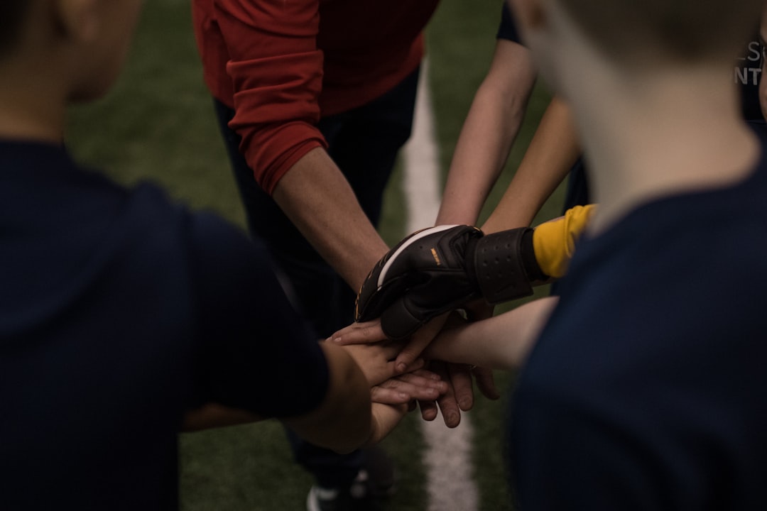 Youth sports players putting their hands together in a team huddle before setting a season goal
