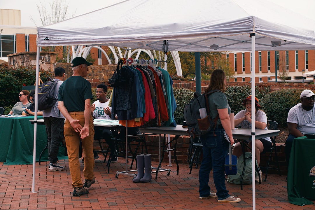 Parents browsing youth sports team apparel and merchandise for sale under a white popup tent