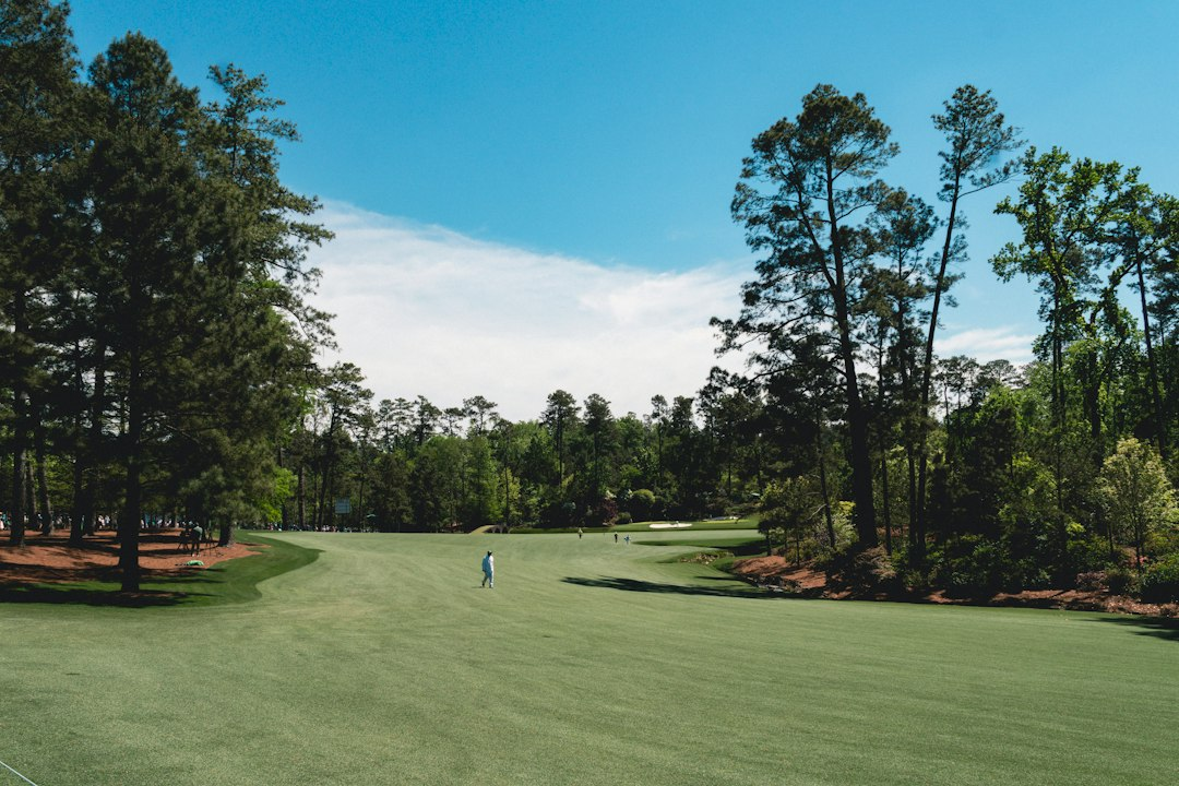 Sunlit golf course fairway lined with trees, the kind of course youth sports teams use for golf tournament fundraisers