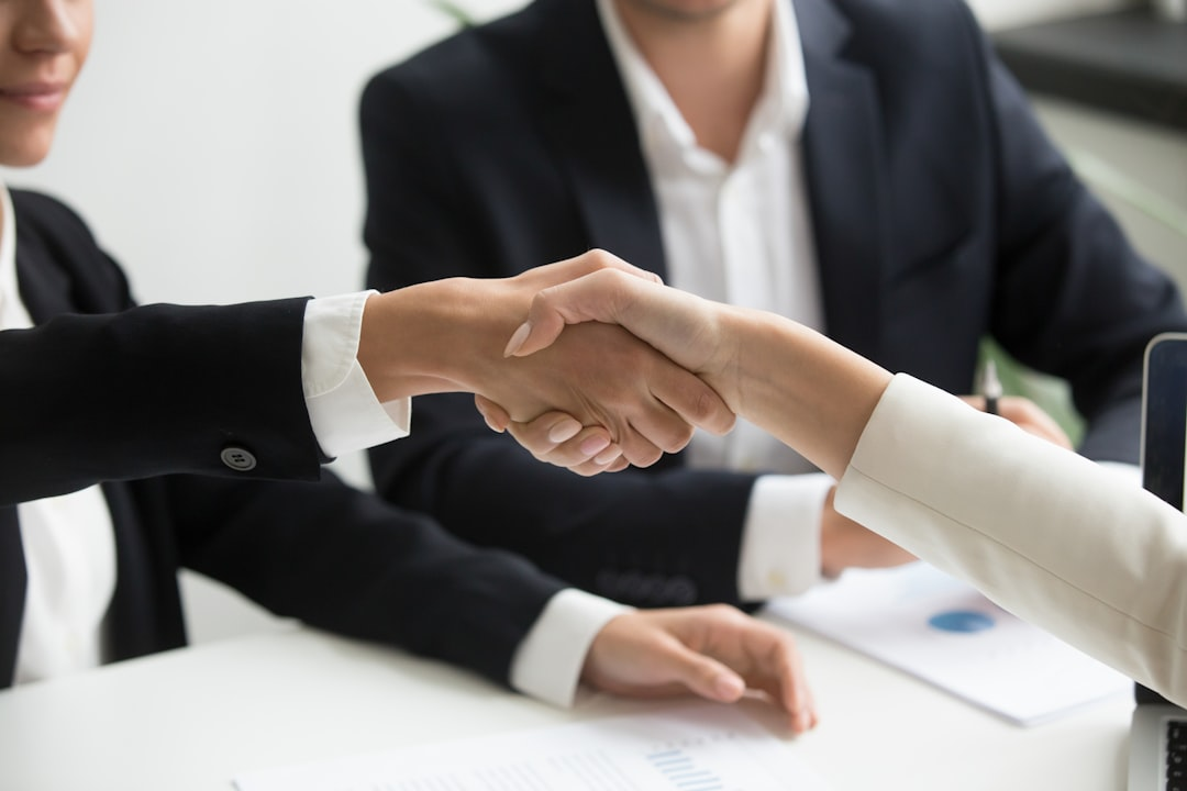 Two people shaking hands over a laptop after agreeing to a fundraising vendor contract